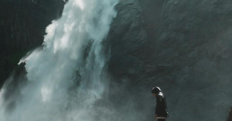 Waterfall Hikes - Man Standing on Brown Rock Cliff in Front of Waterfalls Photography