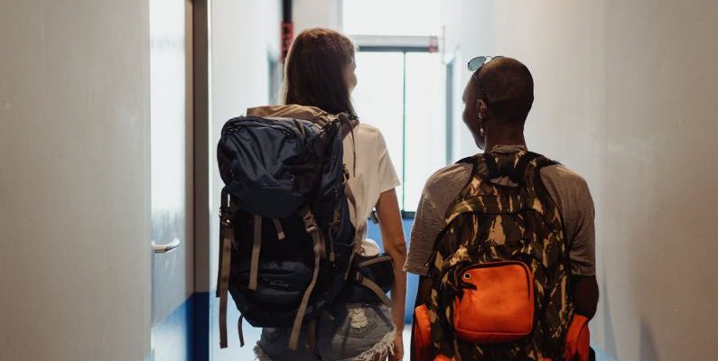 Eco-Friendly Hostel - Women with Backpacks Walking Through the Hostel Corridor