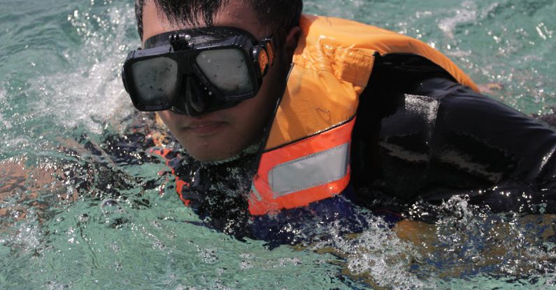Learn To Dive - Crop man in swimming vest and goggles in seawater